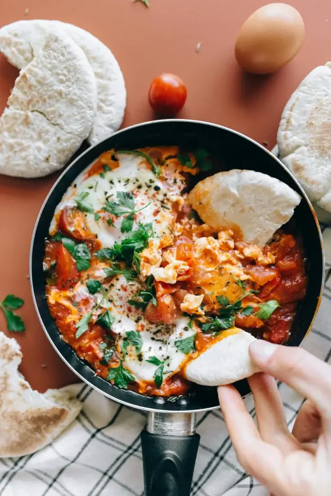 Spicy tomato shakshuka with poached eggs and fresh parsley.