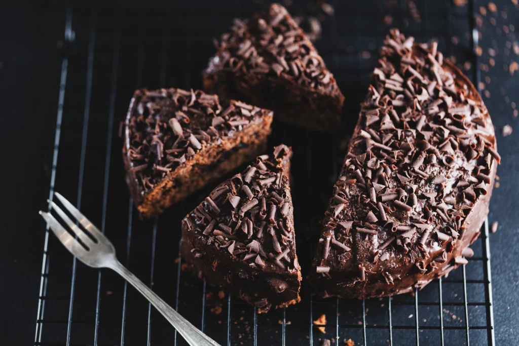 Chocolate fudge cake sliced on a plate, showing the dense, moist crumb and thick layers of dark chocolate frosting