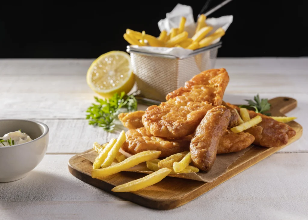 Fish and chips served on newspaper-style parchment, featuring a large golden-brown battered cod fillet and a side of chunky chips