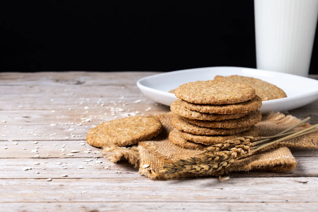 healthy-oatmeal-cookies- Wholewheat digestive biscuits stacked neatly on a wooden board next to a cup of tea.