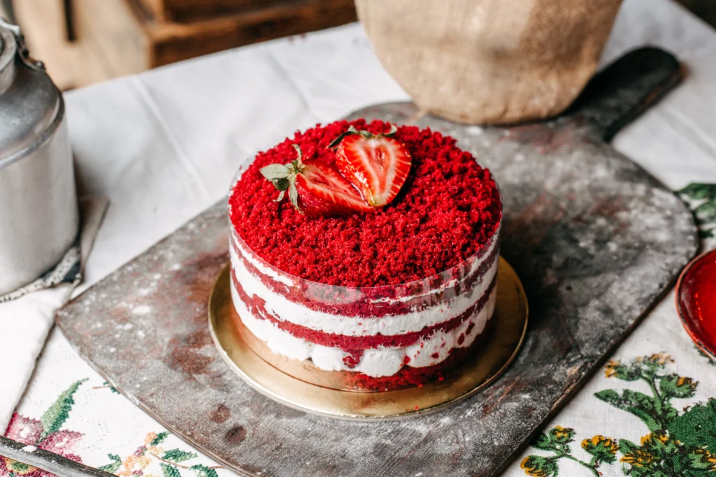 Traditional Victoria Sponge cake garnished with fresh strawberries on a glass cake stand, featuring visible jam and cream filling