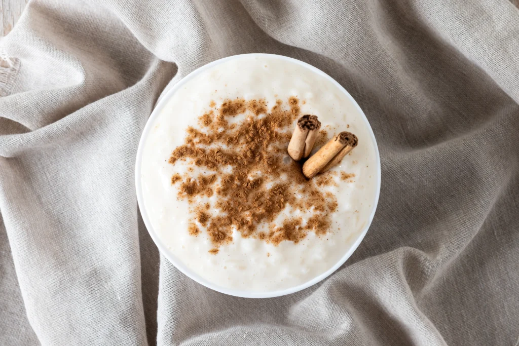 Creamy homemade rice pudding in a ceramic bowl, topped with a dusting of ground cinnamon and a sprinkle of plump golden raisins