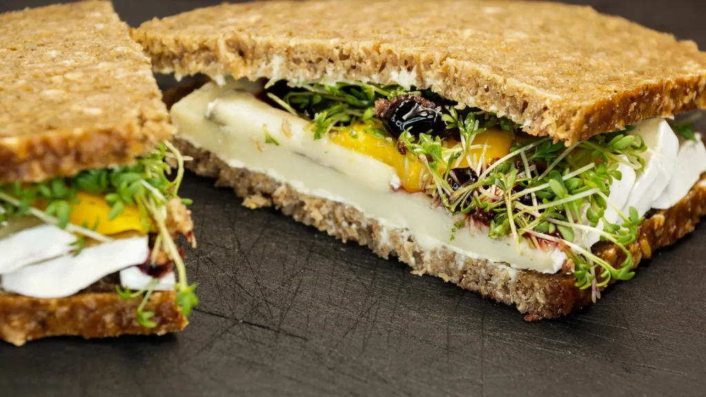 Classic British Egg and Cress sandwich on soft malted grain bread, featuring a creamy chopped egg mayonnaise filling mixed with fresh, peppery garden cress and a hint of white pepper